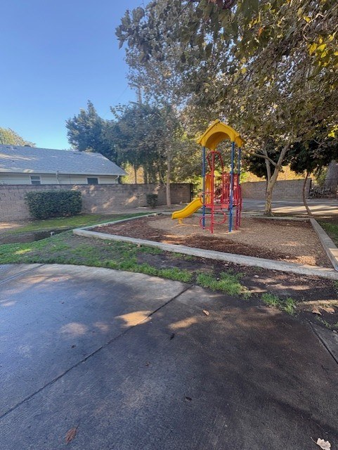 A playground with a yellow slide and red and yellow swings.